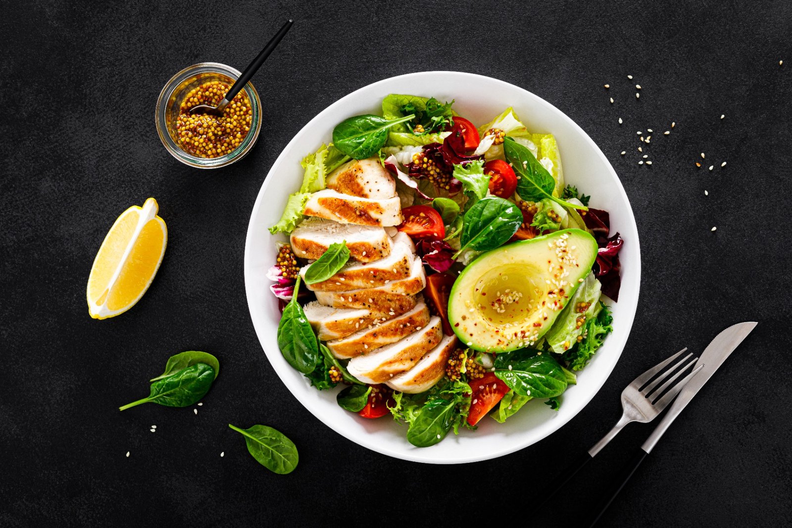 Fresh garden salad in a bowl next to a grilled chicken wrap